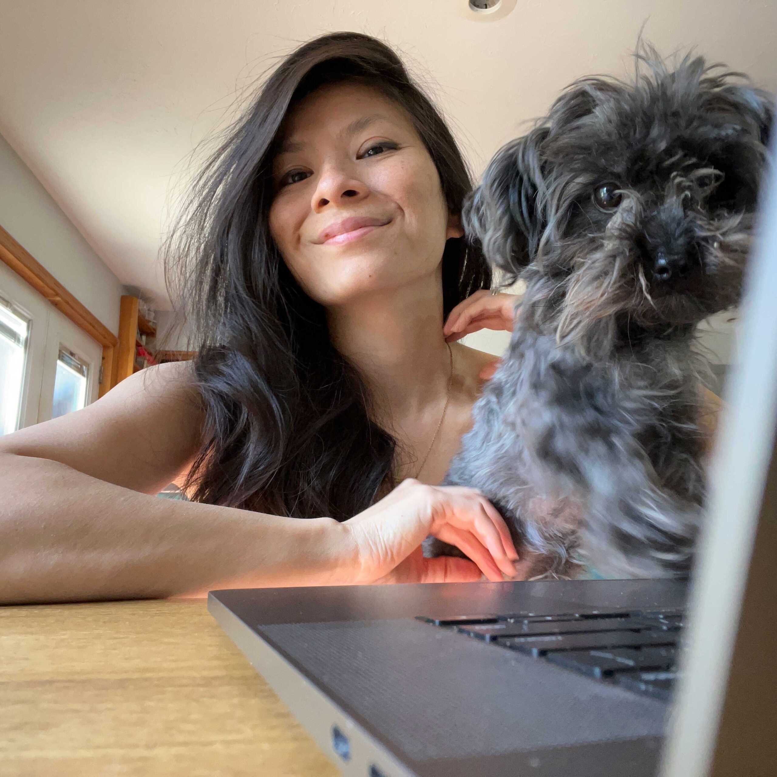Tuyen sits at a desk with her dog Dash