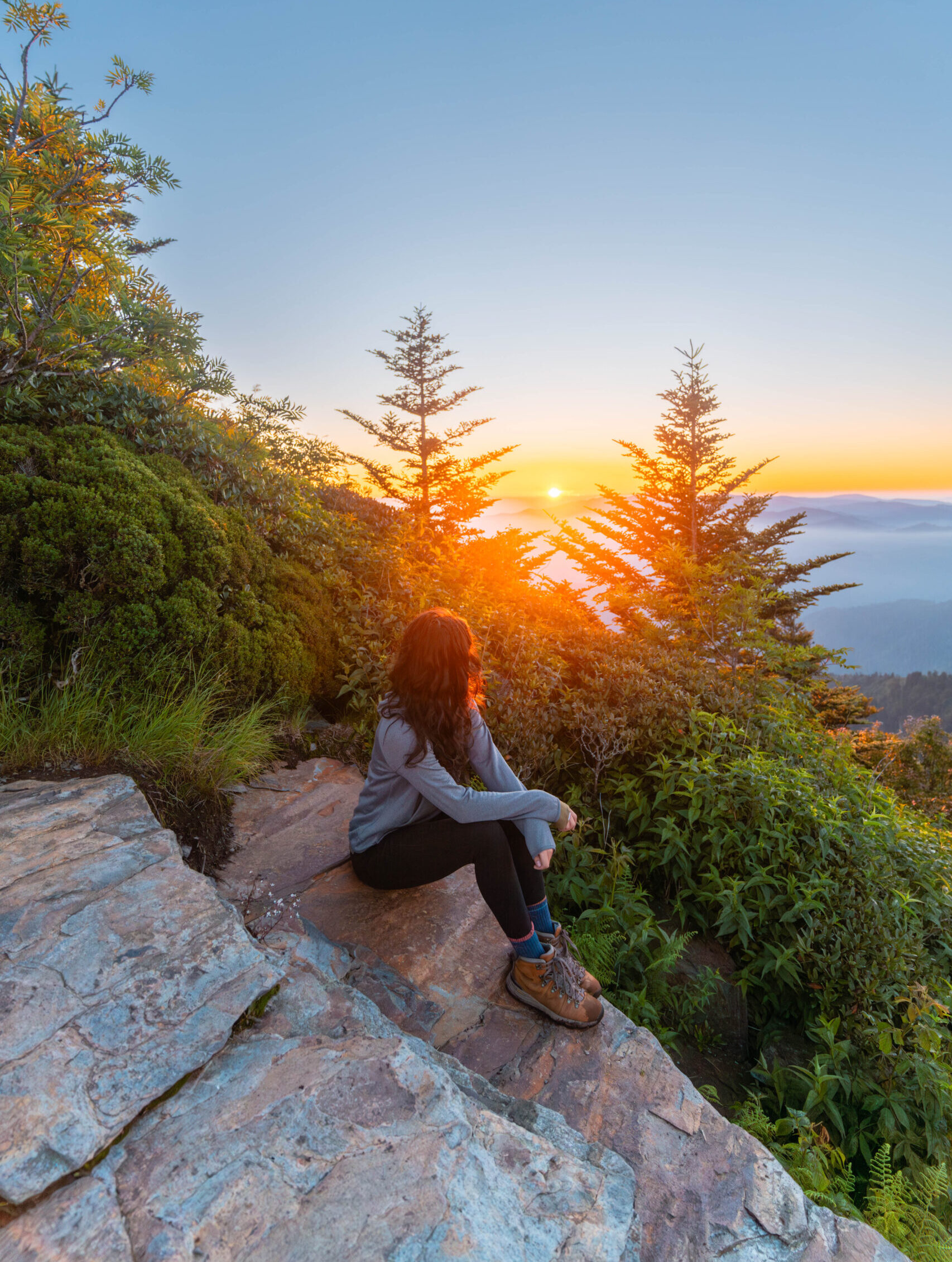 Woman sitting on a rock overlooking sunset in the Gatlinburg mountains.