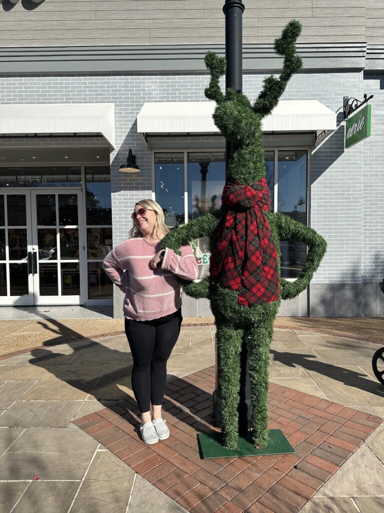 Shianne Warner, social media specialist, posing next to a fake reindeer topiary
