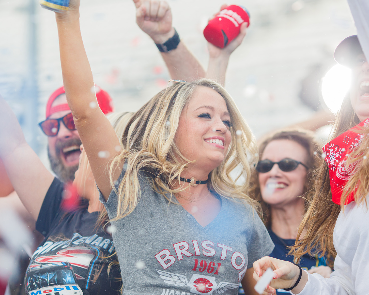 Crowd of people grinning and yelling with arms up.