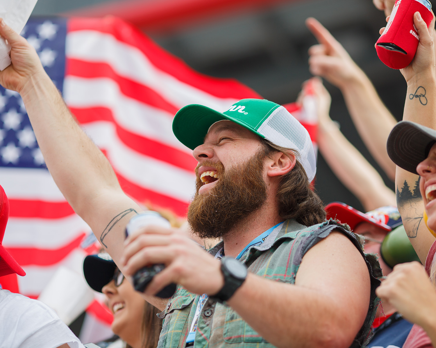 Crowd cheering with American flag in background.