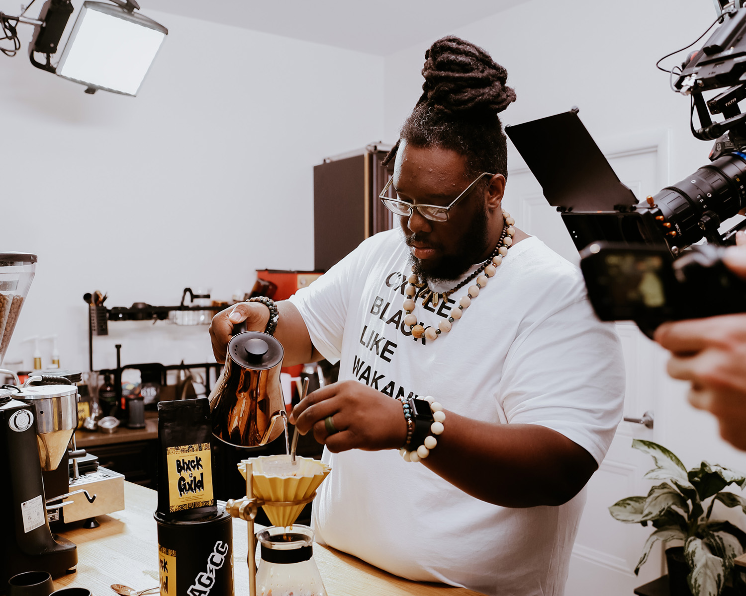 Man pouring coffee as a photographer takes his photo.