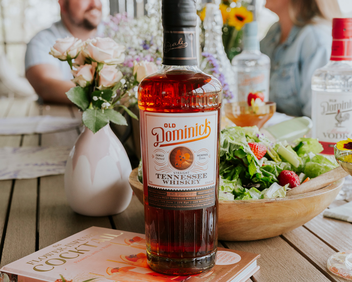 Bottle of ODD whiskey in the foreground at a social gathering.