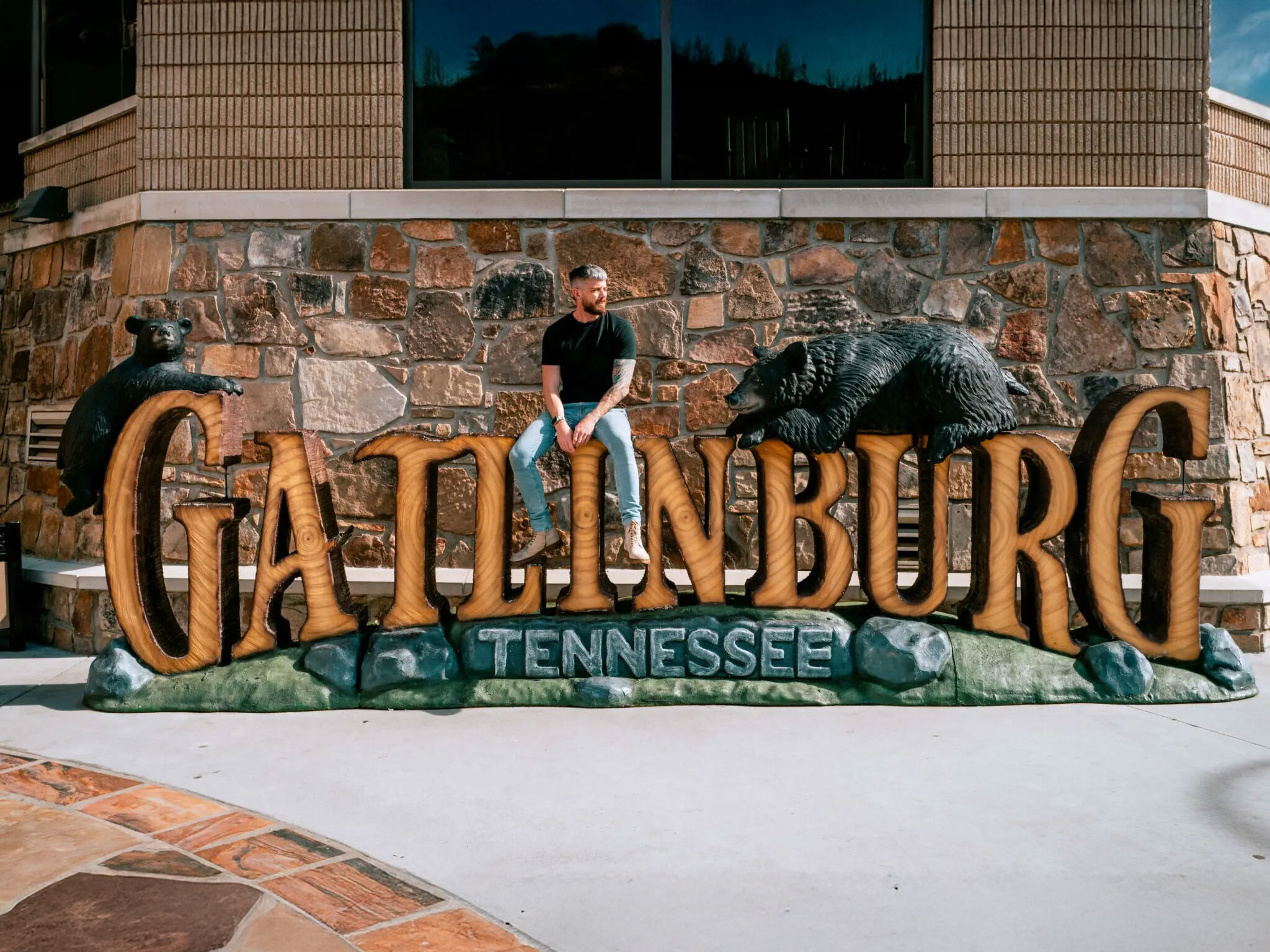 Man sitting on wooden Gatlinburg sign.